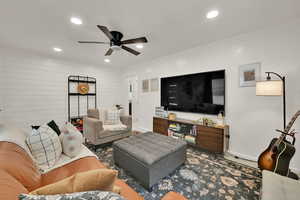 Living room featuring recessed lighting, ceiling fan, and wooden walls