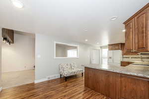 Kitchen with white refrigerator with ice dispenser, dark wood-style flooring, recessed lighting, tasteful backsplash, and a peninsula
