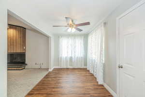 Unfurnished living room with wood finished floors, a ceiling fan, carpet floors, and a large fireplace