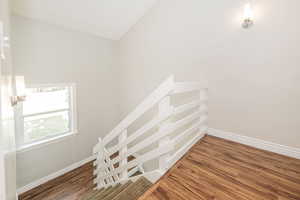 Staircase featuring wood finished floors and lofted ceiling