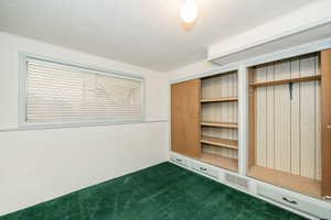 Unfurnished bedroom with dark carpet and two closets