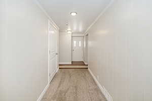 Hallway featuring light carpet and crown molding