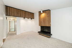 Unfurnished living room with light carpet, a fireplace, and a textured ceiling