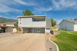 View of front of property with driveway, a mountain view, and a balcony