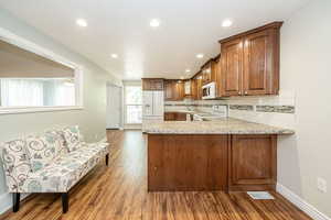 Kitchen with tasteful backsplash, light countertops, dark wood-type flooring, white appliances, and recessed lighting