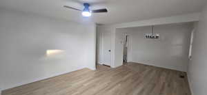 Spare room with wood finished floors, ceiling fan, and a chandelier