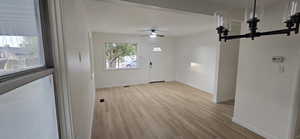 Unfurnished dining area with wood finished floors, a chandelier, and a ceiling fan