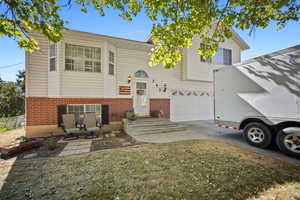 View of front of house with brick siding, a garage, driveway, and a front yard