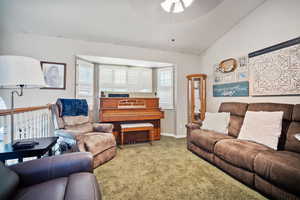 Carpeted living room featuring lofted ceiling and a ceiling fan