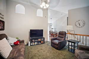 Carpeted living room with high vaulted ceiling and a ceiling fan