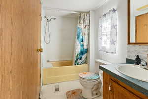 Bathroom featuring vanity, shower / bath combo with shower curtain, a textured ceiling, and backsplash