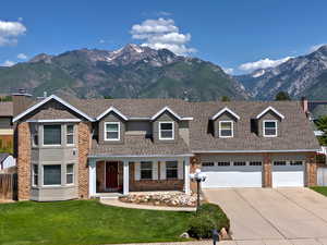 View of front of property with brick siding, driveway, a mountain view, and roof with shingles