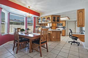 Dining room featuring light tile patterned floors, a desk, a chandelier, and a textured ceiling