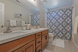 Bathroom with tile patterned flooring, double vanity, and a shower with curtain