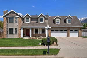 View of front of home featuring concrete driveway, a shingled roof, brick siding, and a garage