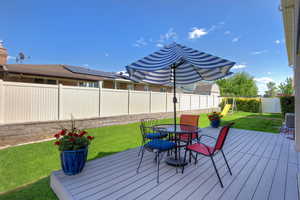 Wooden deck featuring outdoor dining area, a fenced backyard, and a playground