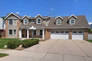 View of front of home with concrete driveway, brick siding, roof with shingles, and an attached garage