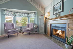 Sitting room with a tile fireplace, carpet, lofted ceiling, and tile patterned flooring