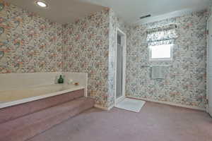 Bathroom featuring a bath, a shower stall, and carpet