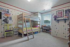 Bedroom with carpet, a textured ceiling, crown molding, and wallpapered walls