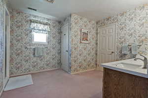 Bathroom with vanity and wallpapered walls