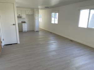 Unfurnished living room featuring light wood-type flooring and baseboards