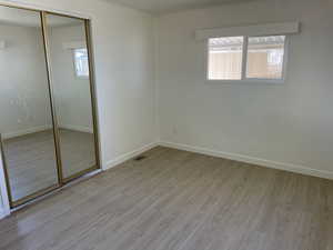 Unfurnished bedroom featuring light wood-style floors, a closet, and crown molding