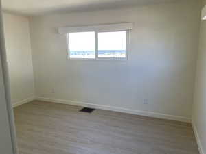 Unfurnished room with light wood-style floors and ornamental molding