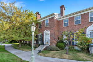 Colonial-style house featuring a chimney, a front lawn, and brick siding