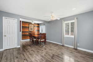 Dining room with wood finished floors, wood walls, and ceiling fan
