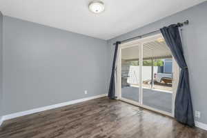 Spare room featuring dark wood-style flooring and baseboards