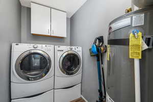Laundry room with cabinet space, washer and clothes dryer, and water heater