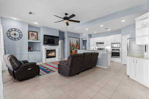 Living area featuring built in shelves, recessed lighting, a ceiling fan, a glass covered fireplace, and light tile patterned floors