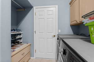Laundry area with washing machine and dryer, cabinet space, and light tile patterned flooring