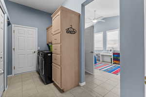 Laundry room with separate washer and dryer, cabinet space, light tile patterned flooring, and a ceiling fan