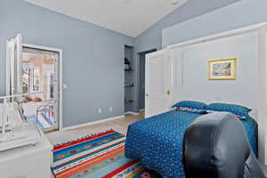 Tiled bedroom featuring vaulted ceiling and baseboards