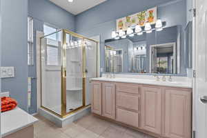 Full bathroom featuring a stall shower, double vanity, and tile patterned flooring