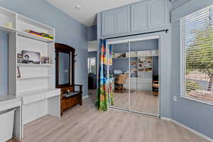 Bedroom featuring a desk, light wood-style floors, and a closet