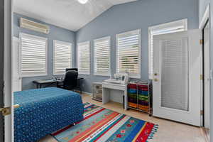 Bedroom with an AC wall unit, lofted ceiling, an office area, tile patterned floors, and ceiling fan