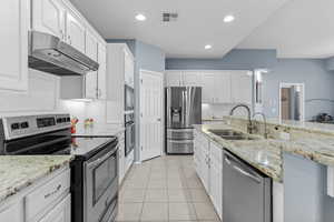 Kitchen featuring stainless steel appliances, light tile patterned floors, white cabinets, and recessed lighting