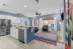 Kitchen with appliances with stainless steel finishes, light tile patterned floors, light stone counters, white cabinetry, and recessed lighting
