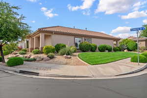 View of front of property with stucco siding, a tiled roof, and a front yard