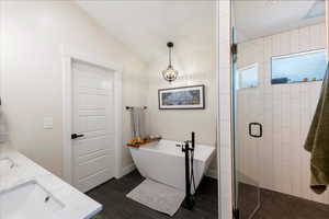 Bathroom with a shower stall, a freestanding tub, double vanity, and vaulted ceiling