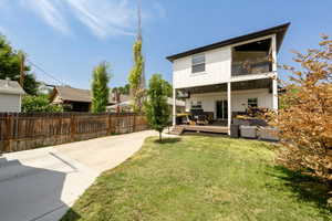 Back of house featuring board and batten siding, a balcony, and a patio