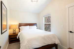 Carpeted bedroom featuring lofted ceiling and baseboards