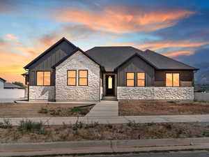 View of front of home with board and batten siding, stone siding, and a shingled roof