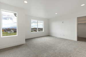 Unfurnished bedroom with carpet, a walk in closet, and recessed lighting