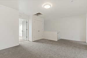 Spare room featuring carpet flooring, attic access, and a textured ceiling