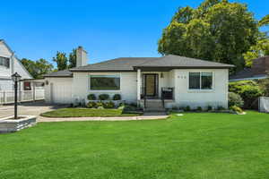 Ranch-style home with brick siding, an attached garage, a chimney, roof with shingles, and driveway