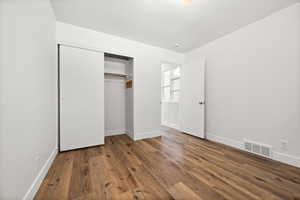 Unfurnished bedroom with wood finished floors and a closet